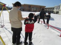 凍った雪の上を教員とともに歩く幼児児童
