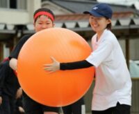 児童と教員が協力して大玉を運んでいる様子。